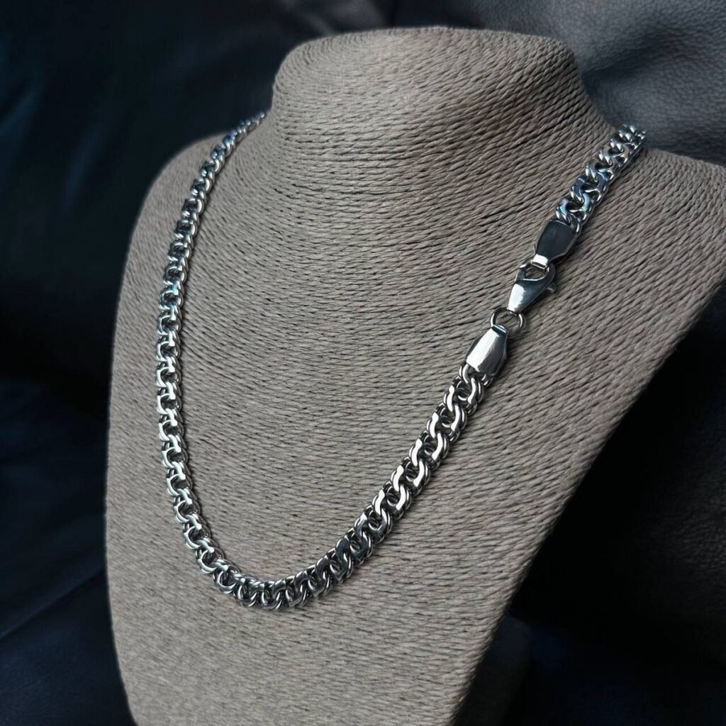 a close-up shot of men's silver chain displayed on stand.