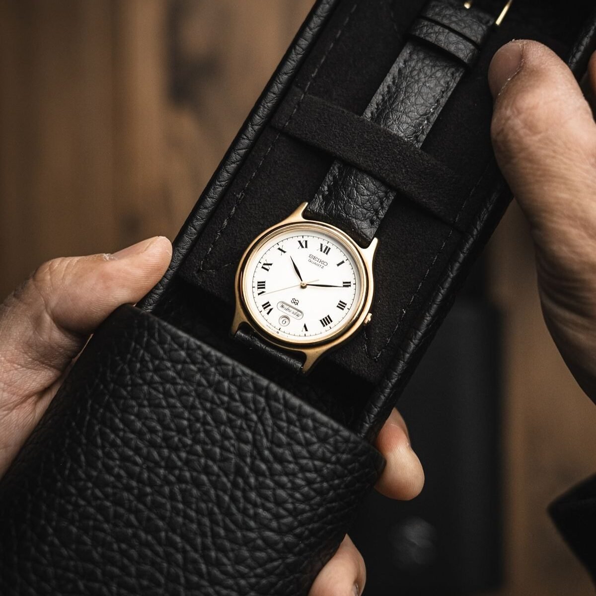 close-up shot of decent dress watch in leather box with white dial and black leather straps.