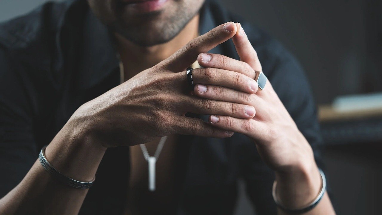 .Close-up of a man's hands wearing affordable men’s jewellery in Pakistan including rings, bracelets, and a necklace.
